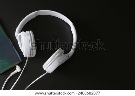 Smartphone and white headphones. Composition for banner on black background