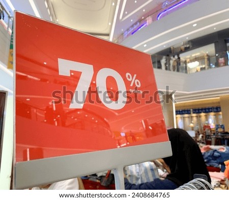 A booth proudly displays huge discount clothing of 70 percent in the center of the world. This ad promotes cheap clothing for Black Friday, reflecting the concept of seasonal sales.