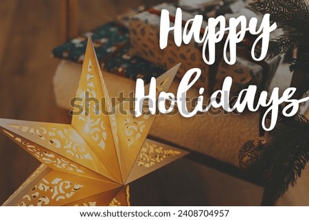 Happy Holidays text on stylish golden christmas star and christmas gifts. Merry Christmas. Season's greeting card. Handwritten sign