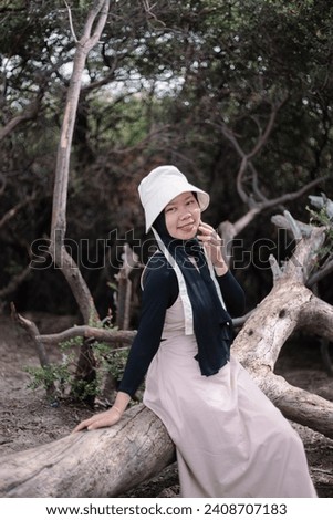 Young Asian girl is sitting on a tree near the Ijen crater. Travel nature concept