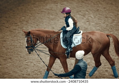 Aerial, top view. Female teacher, instructor teaching little girl, kid horseback riding. Careful ride, outdoor lesson. Sport, childhood, school and educational course, active lifestyle, hobby concept Royalty-Free Stock Photo #2408710435