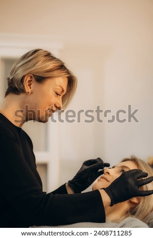 The make-up artist plucks eyebrows with a thread close-up. Women's cosmetology in the beauty salon. Makeup and Cosmetology concept. High quality photo