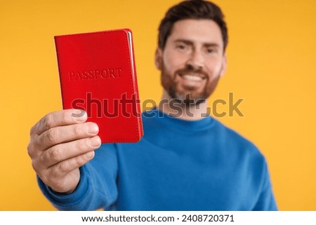 Immigration. Happy man with passport on orange background, selective focus
