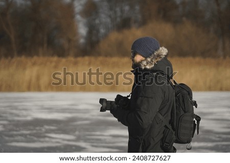 Male landscape photographer outdoors with a camera in his hands, side view. High quality photo