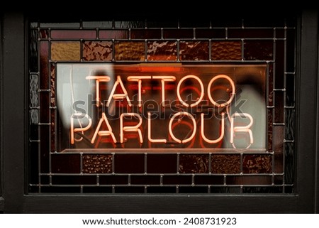 Tattoo parlour parlor logo in neon signs Royalty-Free Stock Photo #2408731923