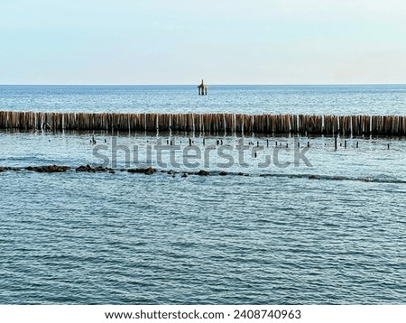 a photography of a person standing on a pier in the water.