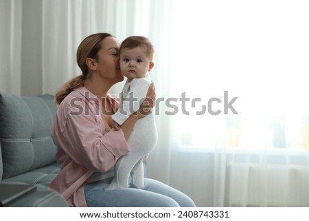 Young woman with her cute baby at home. Space for text