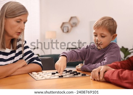 Family playing checkers at wooden table in room