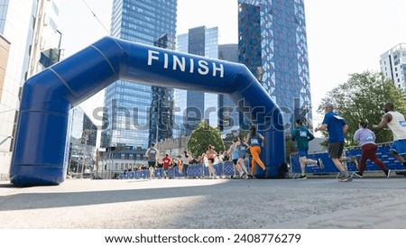 Smiling Group of People Participating in a City Marathon. Wide Shot of Diverse Race Runners Reaching the Finish Line, Celebrating Their Victory and Achieving their Goal Royalty-Free Stock Photo #2408776279