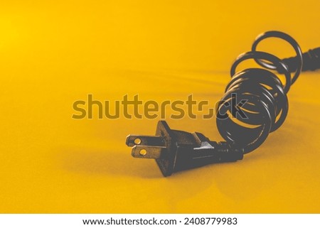 Black electric power outlet cable on yellow background.