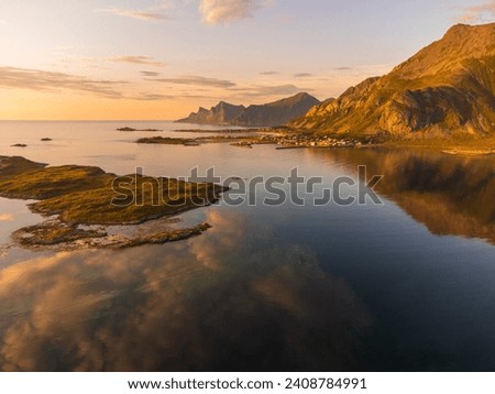 Aerial view of the Ramberg town inlet in Lofoten, Norway with a beautiful sunset light over the fjord sea. Calm waters, reflections. Royalty-Free Stock Photo #2408784991