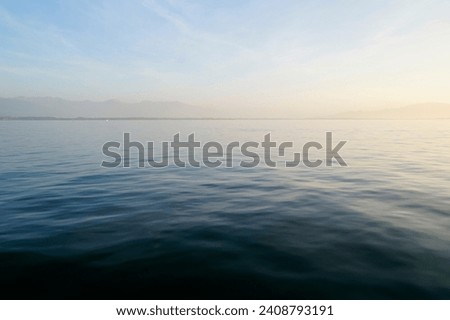 the tranquil transparent waters of lake Constance (Bodensee) with the Swiss Alps in the background on a calm October day on Lindau island, Germany                                Royalty-Free Stock Photo #2408793191
