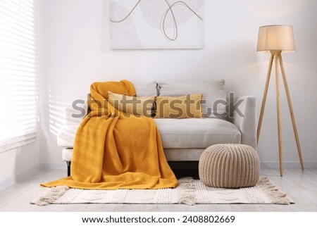 Cozy orange plaid on sofa in living room Royalty-Free Stock Photo #2408802669
