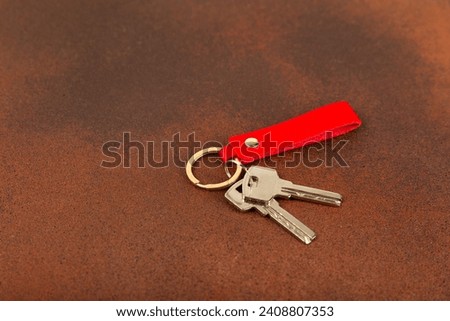 Leather keychain with a key ring on a textured background. Concepts for real estate and moving home or renting property. Buying a property. Mock-up keychain.Copy space.