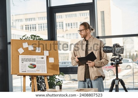 manager with notebook looking at corkboard with graphs during video presentation in modern office