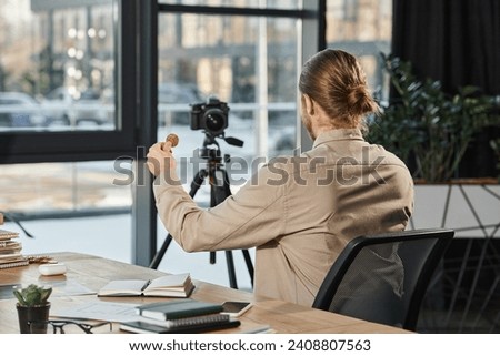 back view of successful businessman showing bitcoin at digital camera at work desk in modern office