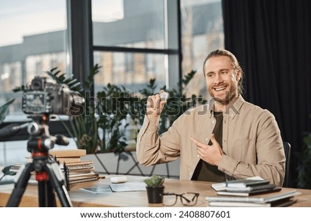 smiling successful entrepreneur showing bitcoin during video blog at workplace in modern office