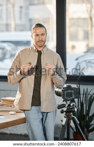 ambitious businessman showing bitcoins in front of digital camera in office, investment marketing