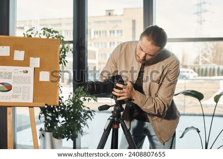 businessman in casual clothes adjusting digital camera near flip chart with infographics in office