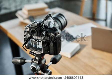 selective focus of digital camera and eyeglasses in office on blurred background, video blog