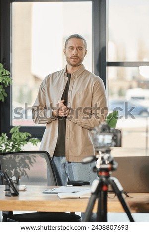 stylish businessman in casual clothes recording video blog on digital camera in contemporary office