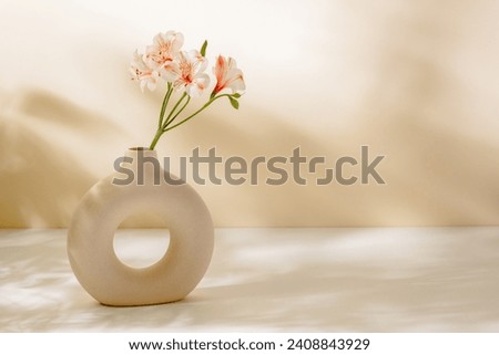 Flower bouquet in stylish vase on the table with sunlight shadows, copy space for design or product presentation. Ceramic vase with pink flowers, aesthetic home poster, interior decoration