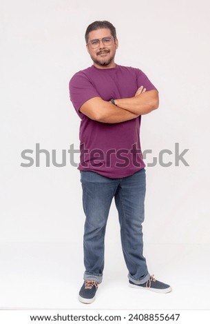 A stocky middle aged man wearing glasses, hands on hips and one foot up. Full body photo, wearing purple waffle shirt and jeans, isolated on a white background. Royalty-Free Stock Photo #2408855647