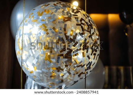Transparent balloon with golden confetti
inside on the party