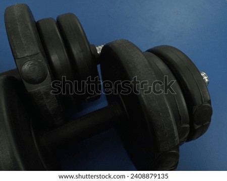 Sports heavy dumbbells on a blue background. A projectile for maintaining physical fitness and pumping up muscles. Topics of sports and arm wrestling.