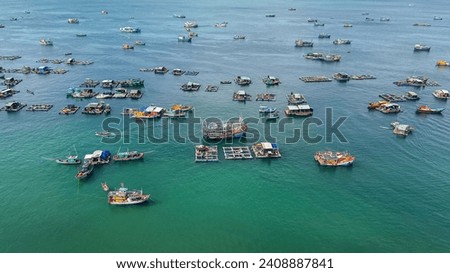 An aerial view of a traditional fishing village with floating houses and various boats on a calm sea
