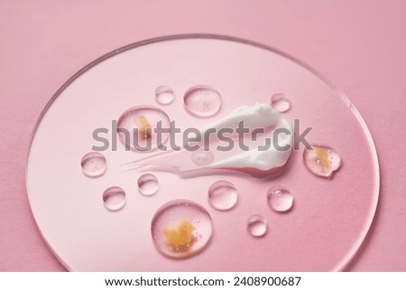 Gel, serum and a cream on a transparent round stand on a pink background.