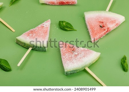 Frozen watermelon popsicles on trendy Savannah green background. Refreshing summer dessert, flat lay, close up