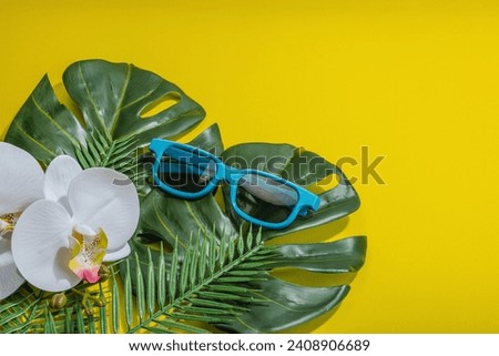 Summer vacation concept. Sunglass, marine decor, palm and monstera leaves, orchid flower. Bright yellow background, hard light, dark shadow, flat lay, copy space