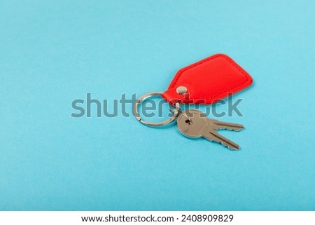 Leather keychain with a key ring on a blue background. Concepts for real estate and moving home or renting property. Buying a property. Mock-up keychain.Copy space.