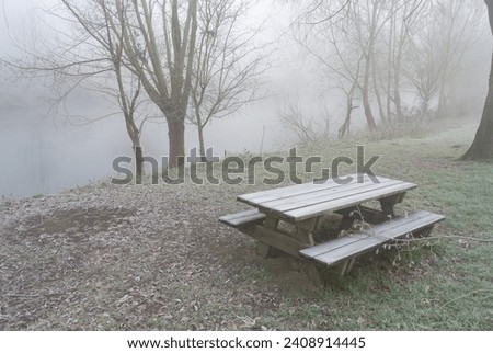 A frozen pic-nic table near the eure river in the mist of a french winter morning