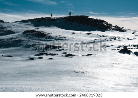 silhouette of two mountaineers on top of a snow-capped mountain, impressive copy space photograph .