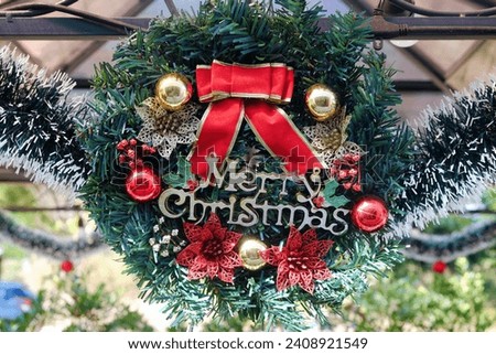 Merry Christmas badge with shiny balls and red ribbon on green decoration