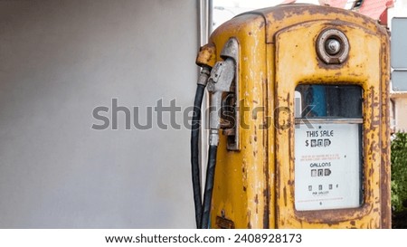 Old yellow rusty American gas pump, empty wall background on the left