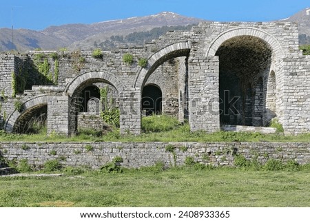 Remains of stepped arcade of four arches -in crescendo, alternately one half-sized, the next complete- made of stone block masonry on the upper-central courtyard of the fortress. Gjirokaster-Albania. Royalty-Free Stock Photo #2408933365