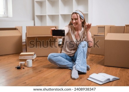 Excited ginger woman with braids showing  key of her new home and taking selfie.