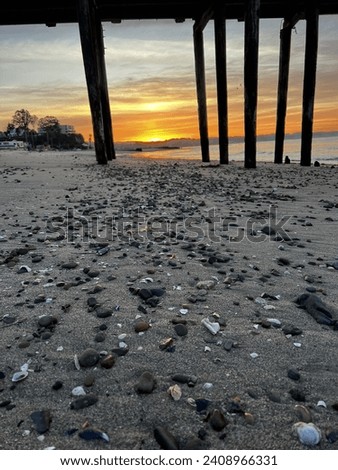 Here is the sunrise on Hopper Beach in Capitola, California. A view of the shells, and Capitola wharf with the Aptos hills getting the first peak of the sun. Royalty-Free Stock Photo #2408966331