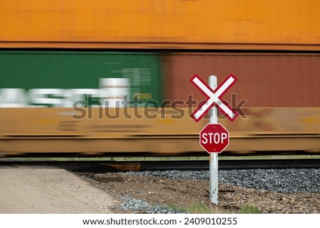 Blurred freight train cars moving past a rural railway crossing.