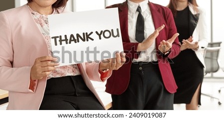 Group of businesspeople join together greeting and hold thank you word for sign of thankfulness to someone in modern office. Idea for good teamwork feeling declaration and support for colleagues.
