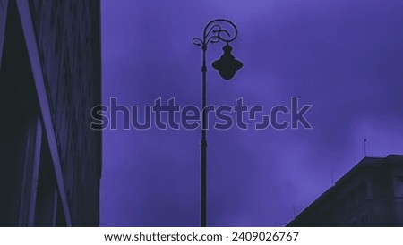 Street lamp silhouette next to a building with a foggy, dark sky background