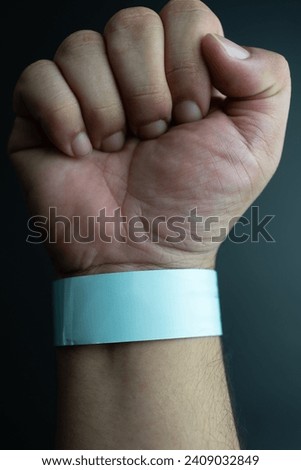 Blue paper wristband mockup on persons arm. Empty adhesive bangle wristlet sticker on male hand, blue paper bracelet, check tape, event ticket concept