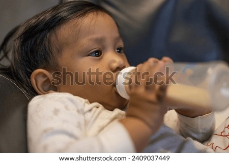 Baby Drinking Milk From The Bottle.  Close up of feeding baby with milk infant hold bottle.