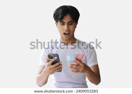 A young handsome man making money from a cellphone app. Holding cash on one hand. Income generation or mobile banking concept.isolated on a White background. Royalty-Free Stock Photo #2409053283