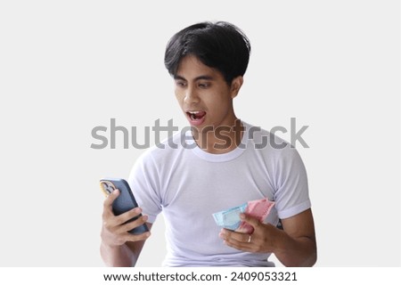 A young handsome man making money from a cellphone app. Holding cash on one hand. Income generation or mobile banking concept.isolated on a White background. Royalty-Free Stock Photo #2409053321