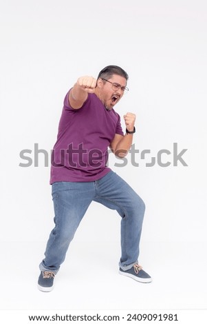 A overweight middle aged guy makes a funny looking punch. Overwhelmed with joy. Full body photo, isolated on a white background.
