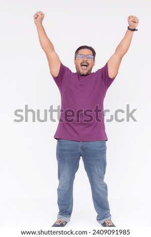 A man, feeling exhilarated, throwing his hands in the air. Celebrating victory, overwhelmed with joy. Full body photo, isolated on a white background. Royalty-Free Stock Photo #2409091985